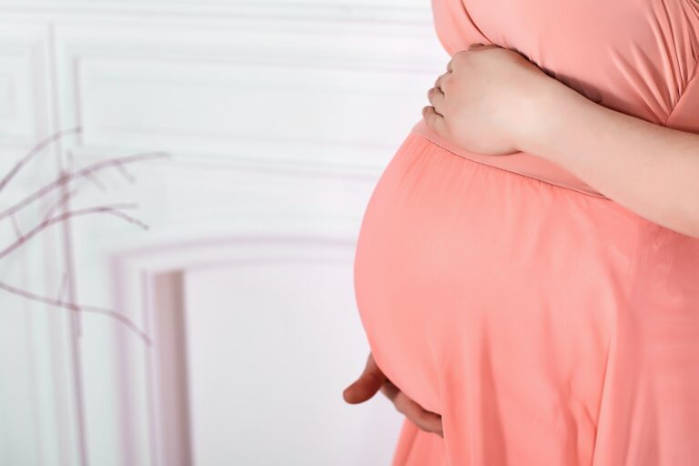 Pregnant woman holding her belly studio background photo.