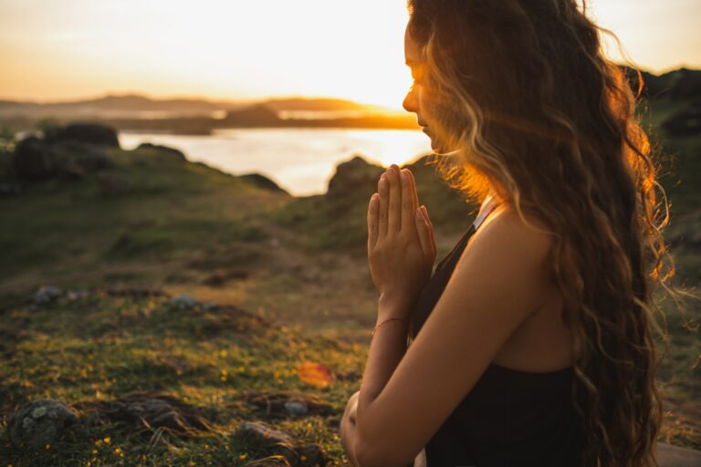 Woman praying alone at sunrise. Nature background. Spiritual and emotional concept